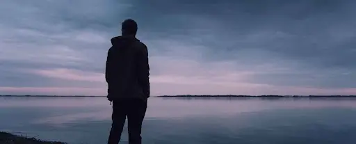 Solitary man looking into a lake at dusk